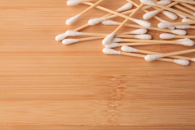Photo of Heap of clean cotton buds on wooden table, flat lay. Space for text