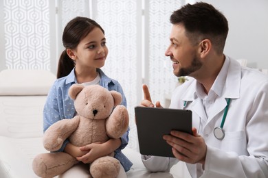 Photo of Pediatrician explaining physical examination result to little girl in hospital