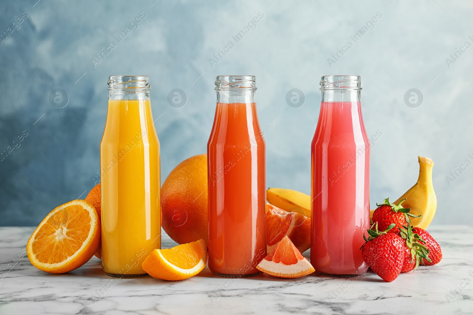 Photo of Bottles with tasty juices and ingredients on table