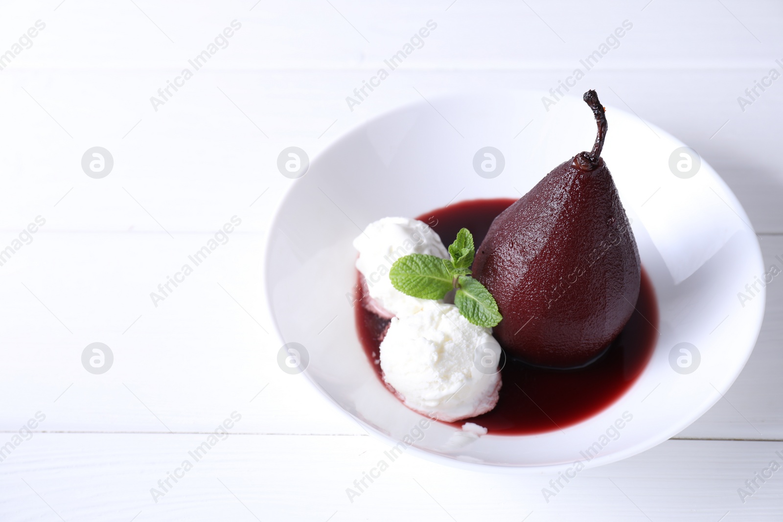Photo of Tasty red wine poached pear with mint and Ice cream on white wooden table, closeup. Space for text