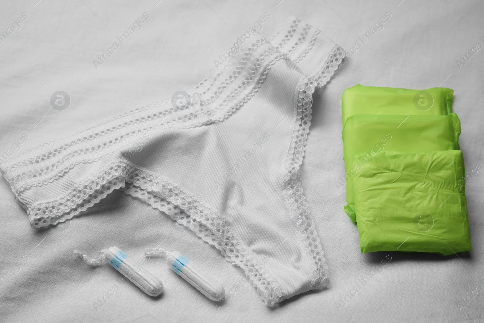 Photo of Woman's panties, menstrual pads and tampons on white fabric