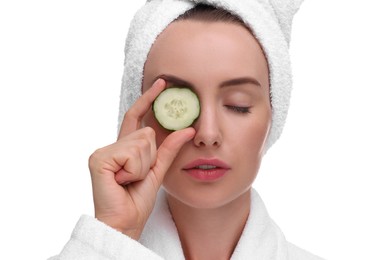 Photo of Beautiful woman in bathrobe covering eye with piece of cucumber on white background