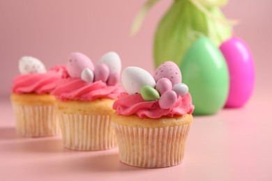 Photo of Tasty decorated Easter cupcakes on pink background, selective focus