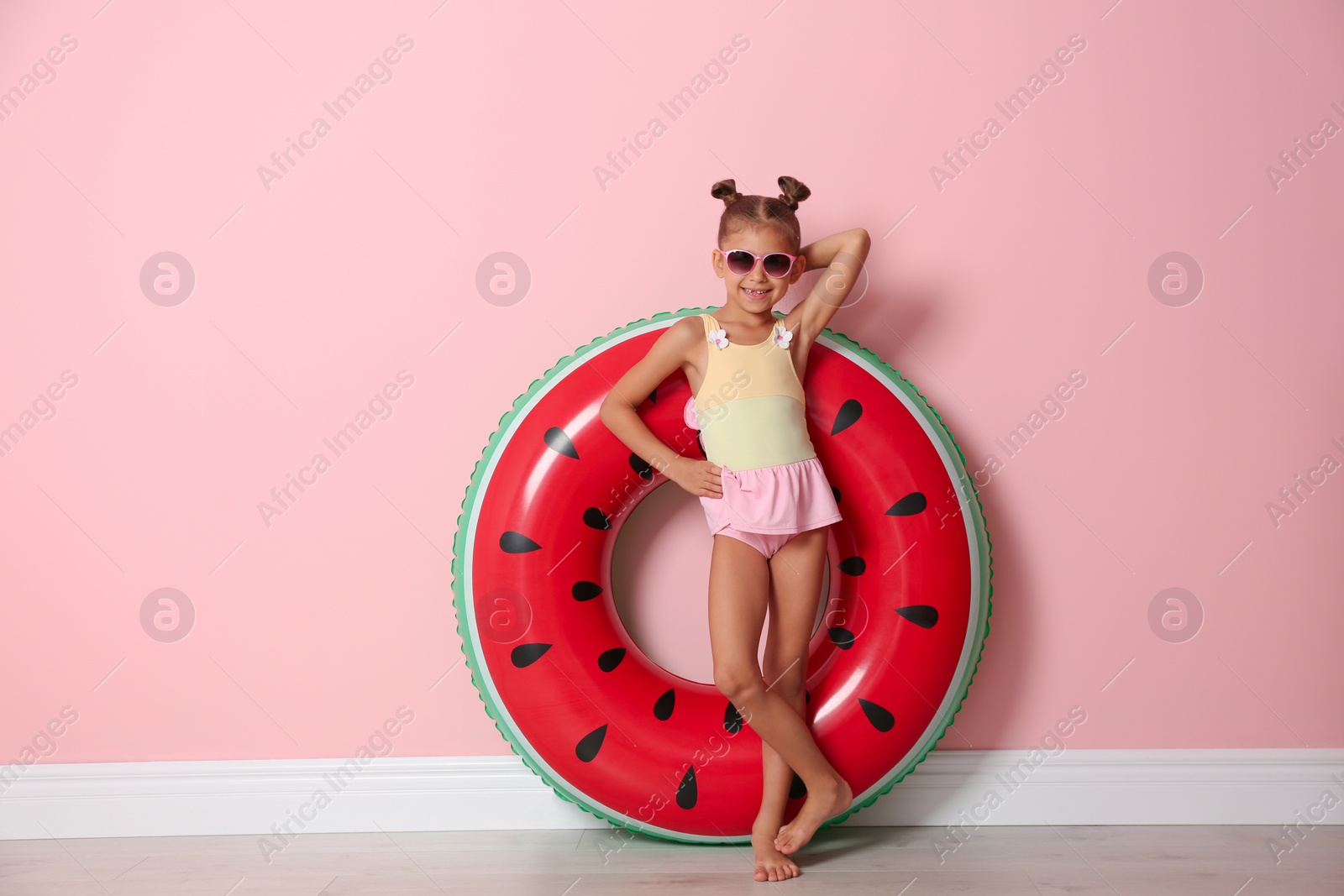 Photo of Cute little girl with inflatable ring near color wall