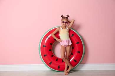 Photo of Cute little girl with inflatable ring near color wall