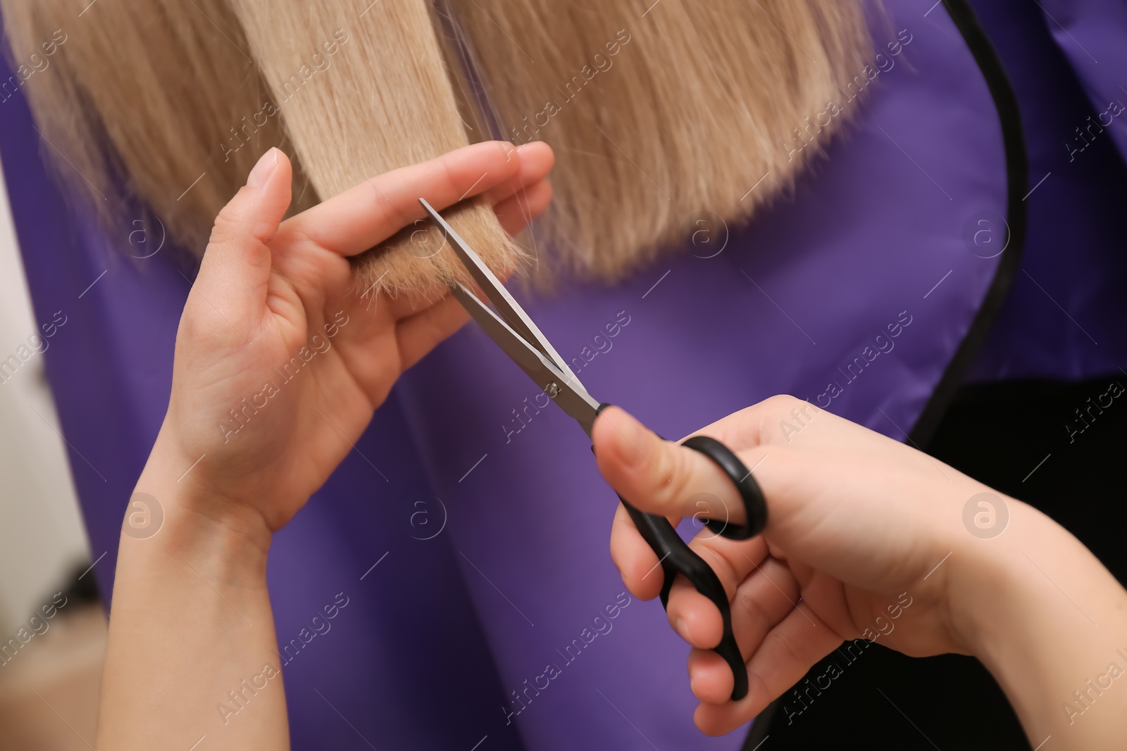 Photo of Stylist cutting hair of client in professional salon, closeup