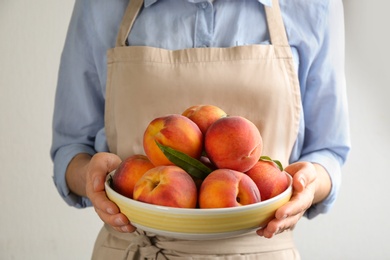 Woman with fresh sweet peaches in plate, closeup