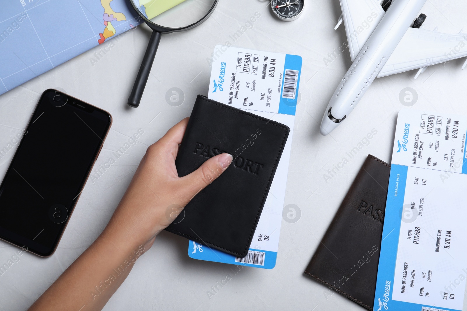 Photo of Woman with passport and airline ticket at white table, top view. Travel agency concept