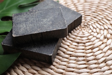 Natural tar soap on wicker mat with green leaf, closeup