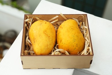 Photo of Delicious ripe yellow mangoes in wooden box outdoors