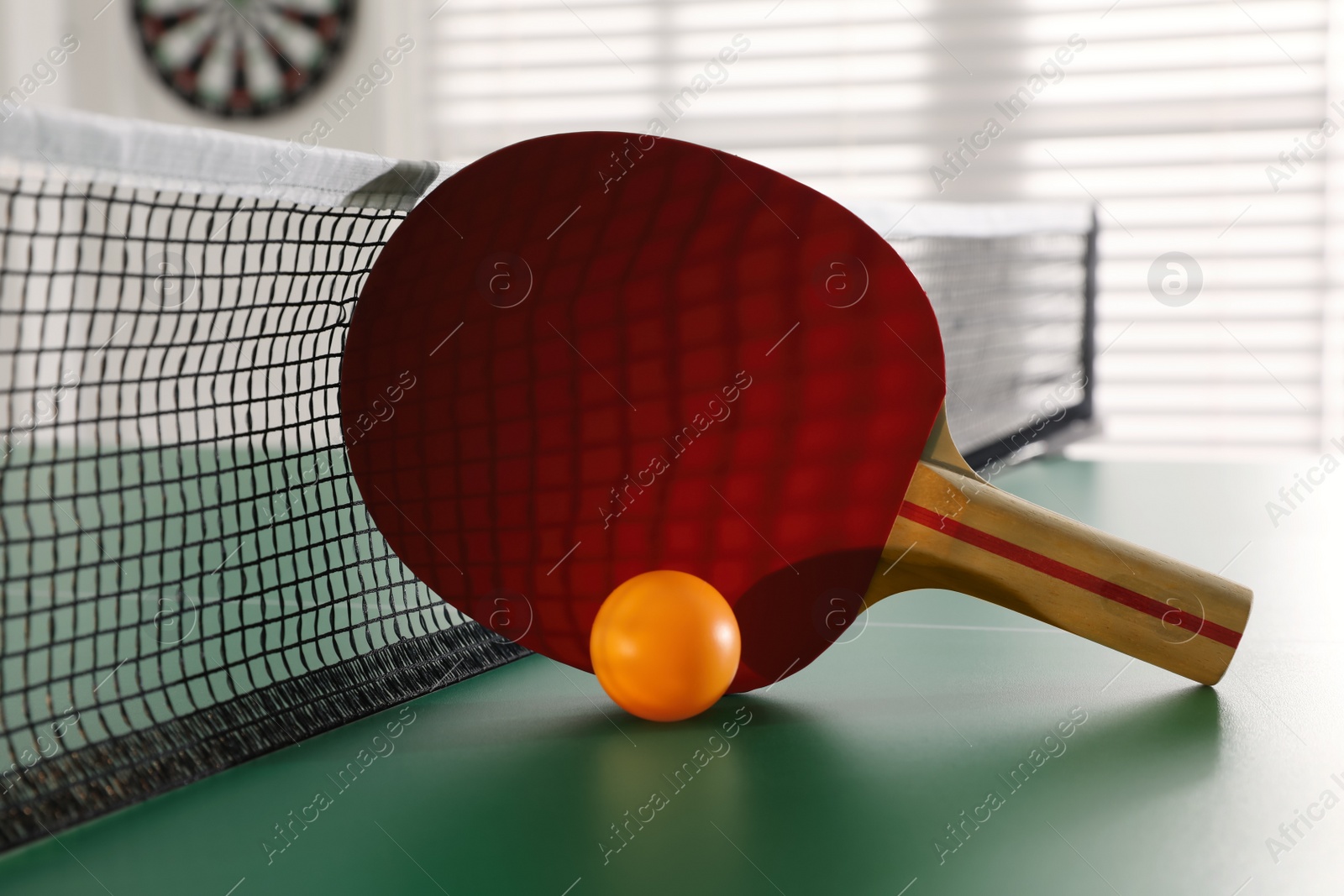 Photo of Racket and ball near net on ping pong table indoors