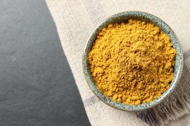 Photo of Dry curry powder in bowl on dark table, top view. Space for text