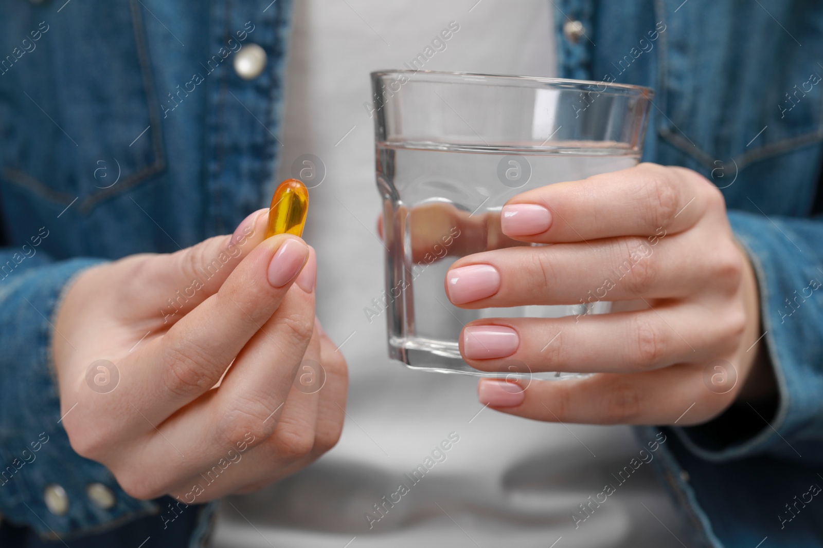 Photo of Woman holding glass of water and pill, closeup view