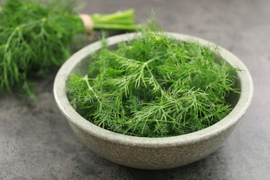 Bowl of fresh dill on grey table, closeup