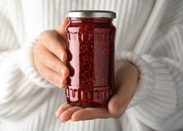 Woman with jar of raspberry jam, closeup