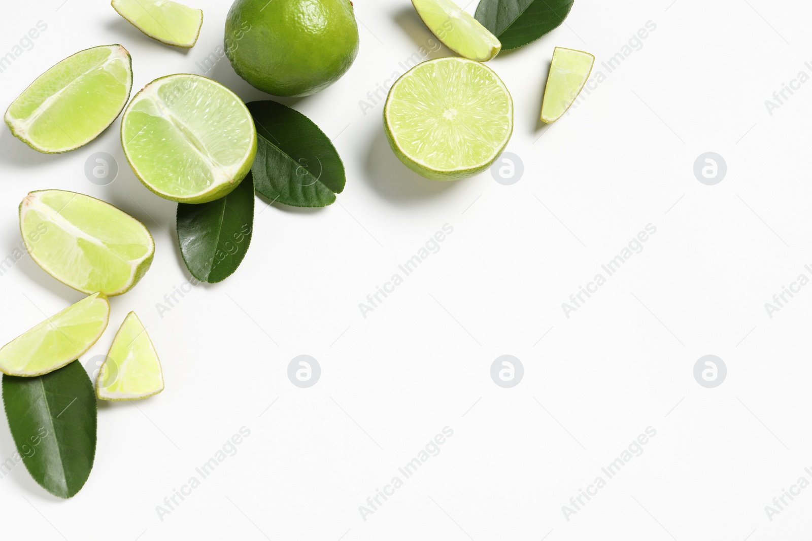Photo of Fresh ripe limes and leaves on white background, flat lay. Space for text