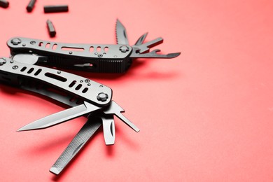 Photo of Compact portable black multitool and details on red background, closeup. Space for text