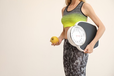 Photo of Woman holding fresh apple and scales on light background. Healthy diet