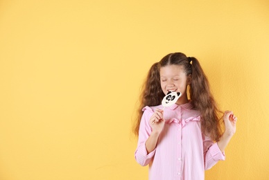Photo of Little girl with candy on color background. Space for text