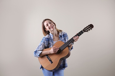 Photo of Young woman playing acoustic guitar on grey background