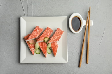 Photo of Fresh crab sticks with cucumber served on grey table, flat lay