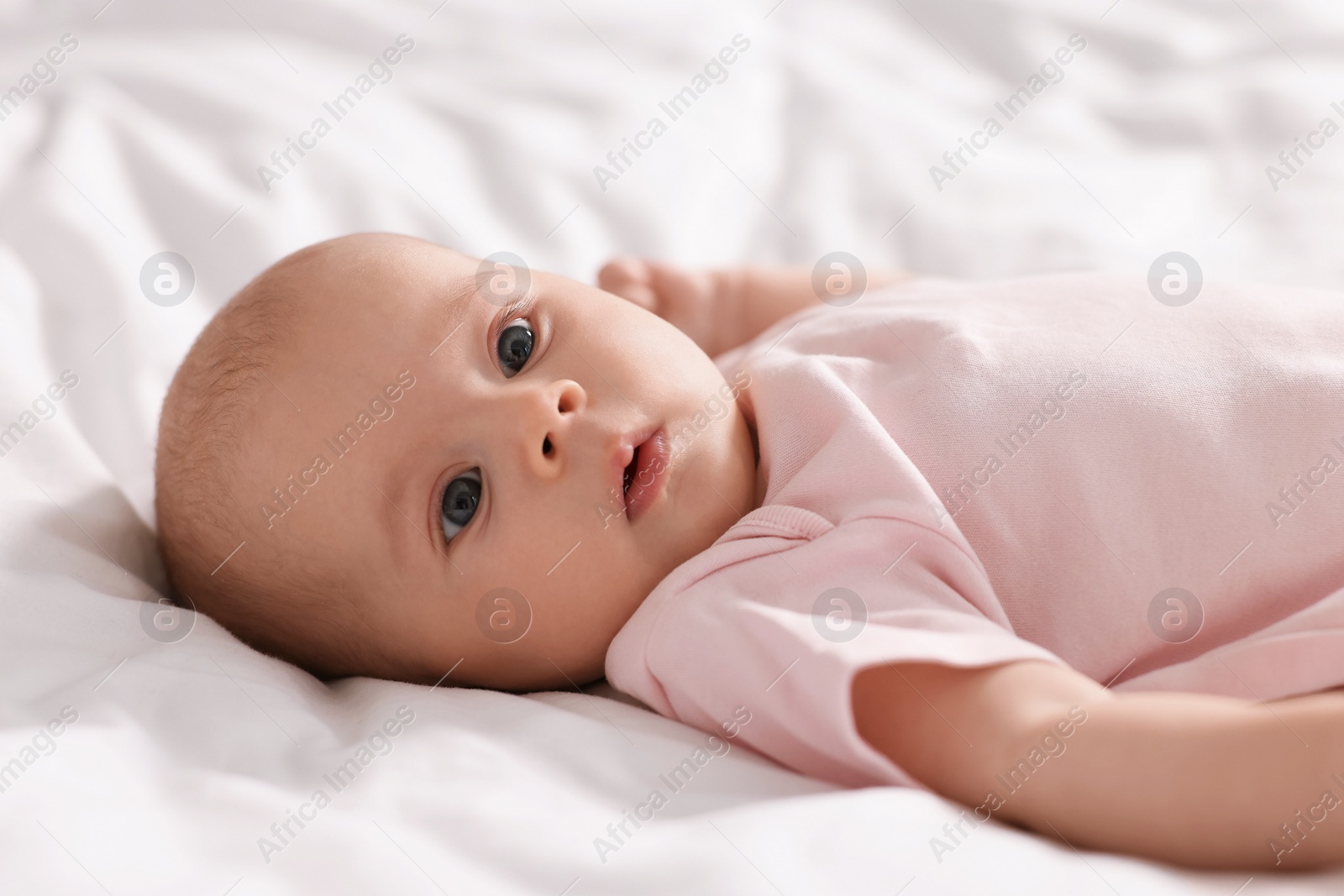 Photo of Cute little baby lying on white sheets