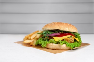 Photo of Delicious burger with tofu and fresh vegetables on white table, space for text