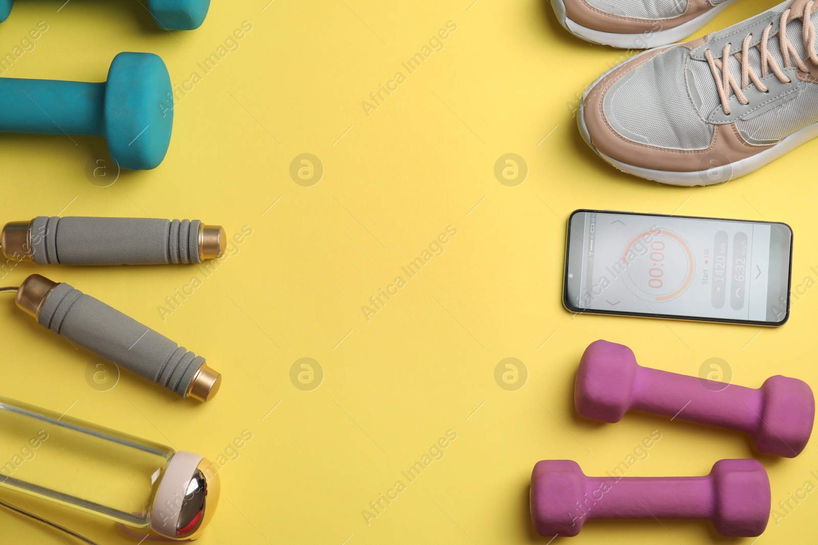 Photo of Smartphone with timer and fitness accessories on yellow background, flat lay. Space for text