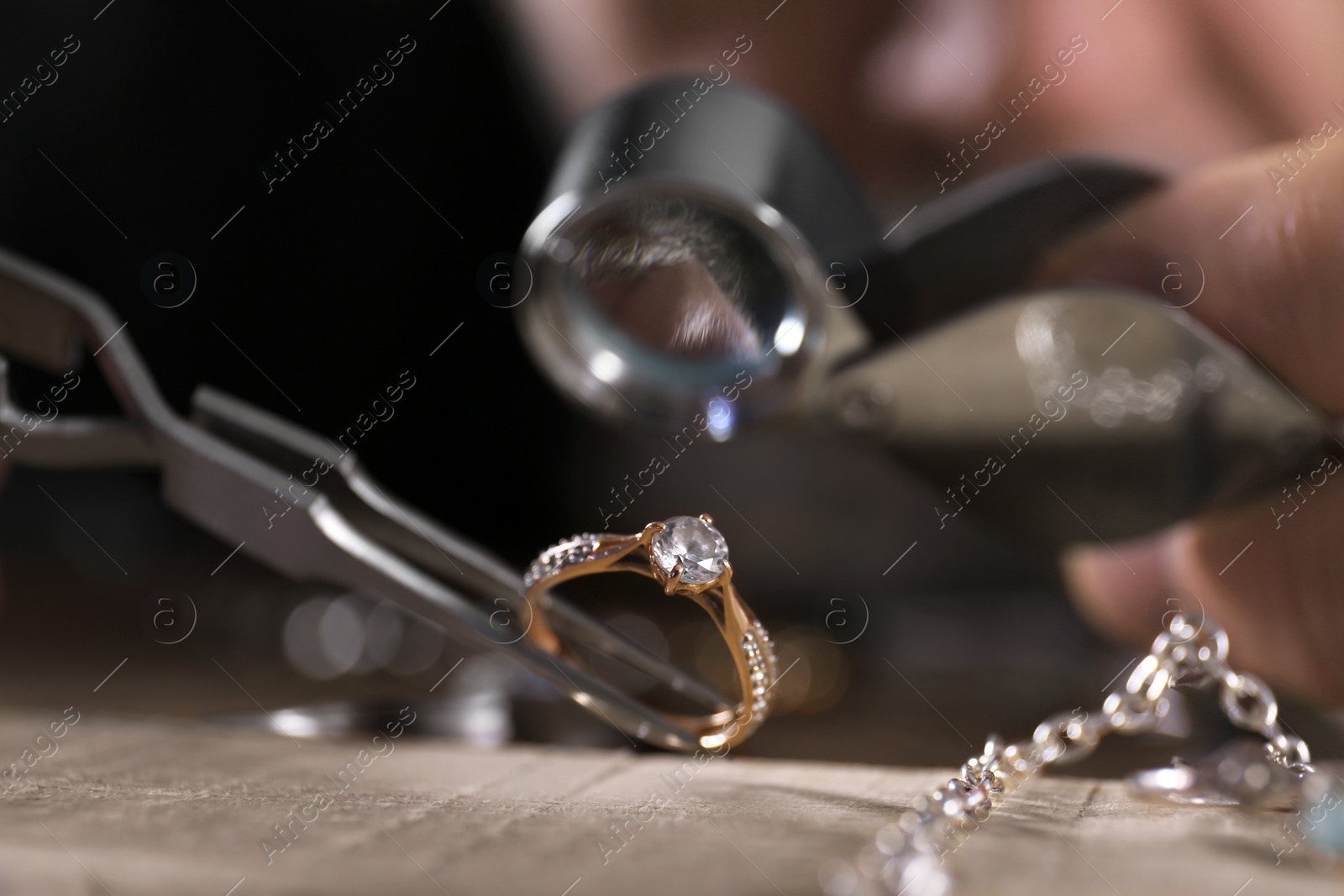 Photo of Male jeweler examining diamond ring in workshop, closeup view