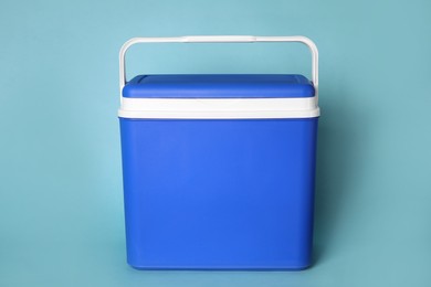 Closed blue plastic cool box on turquoise background