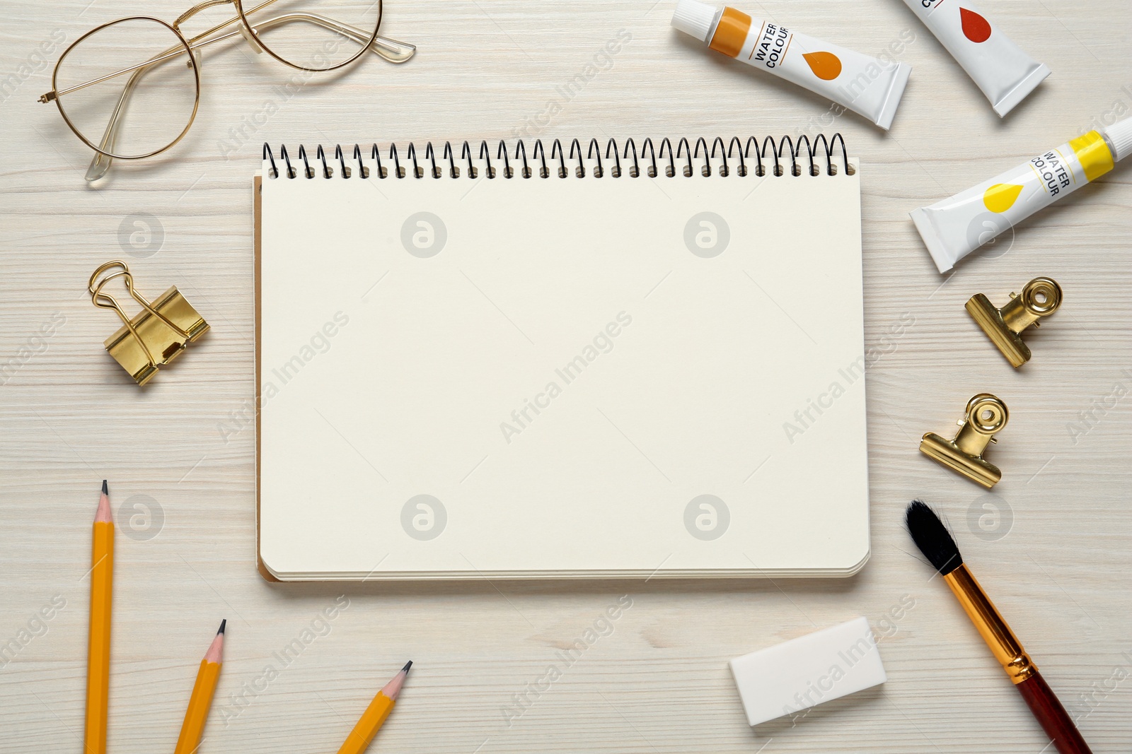 Photo of Flat lay composition with blank sketchbook on white wooden table. Space for text