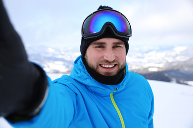 Young man taking selfie at mountain resort. Winter vacation