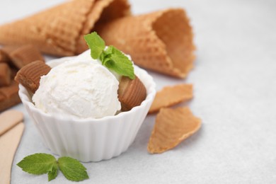 Scoops of tasty ice cream with mint leaves and caramel candies on white table, closeup. Space for text