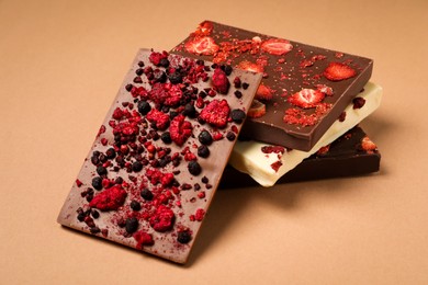 Different chocolate bars with freeze dried fruits on beige background