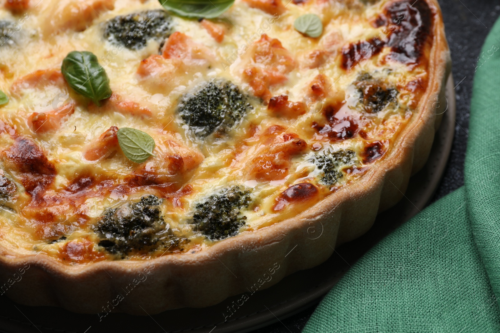 Photo of Delicious homemade quiche with salmon and broccoli on table, closeup