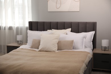 Photo of Many soft white pillows and blanket on bed indoors