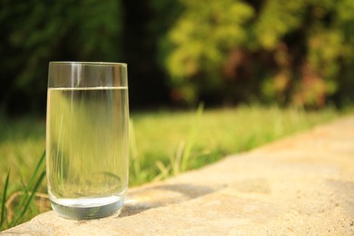 Photo of Pouring fresh water on stone surface outdoors, space for text