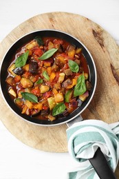 Frying pan with tasty ratatouille on white wooden table, top view