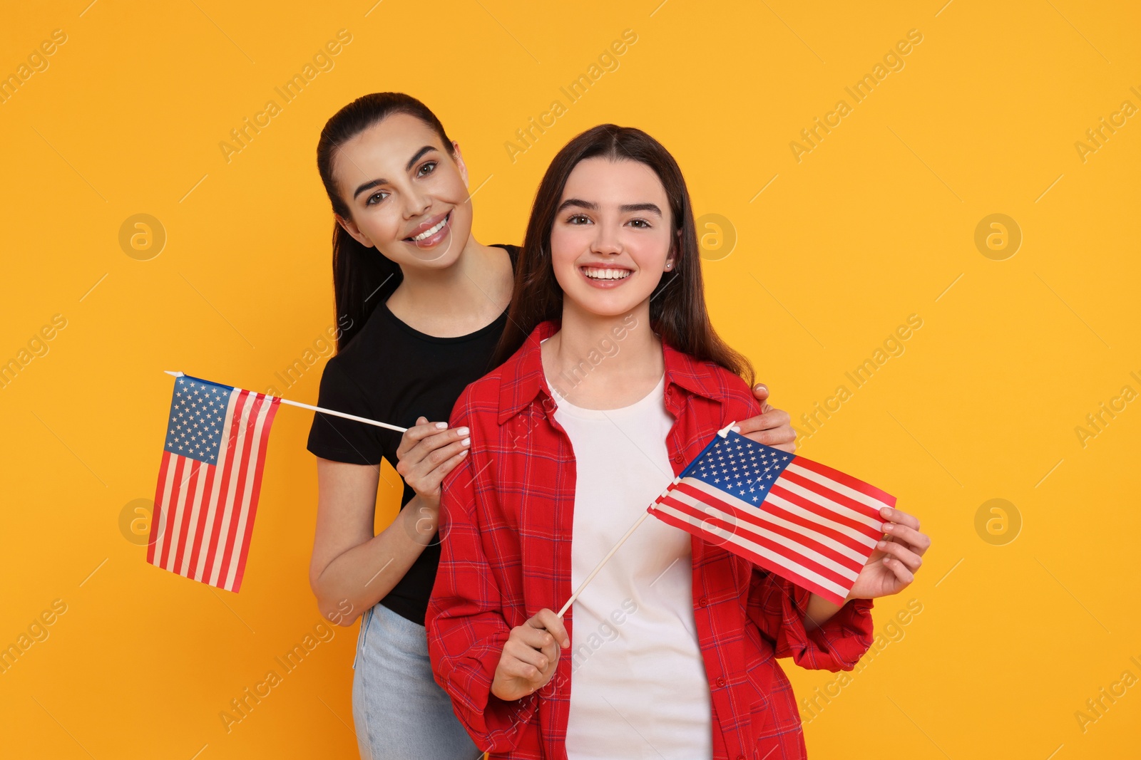 Photo of 4th of July - Independence Day of USA. Happy woman and her daughter with American flags on yellow background