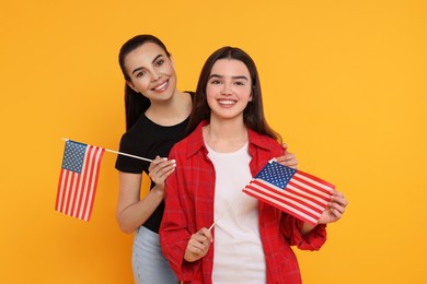 Photo of 4th of July - Independence Day of USA. Happy woman and her daughter with American flags on yellow background