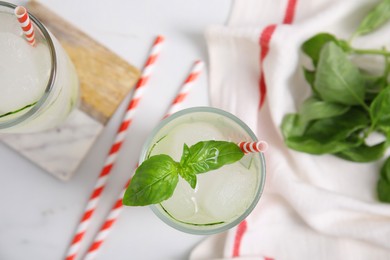 Photo of Glass of refreshing cucumber water with basil on white table, flat lay