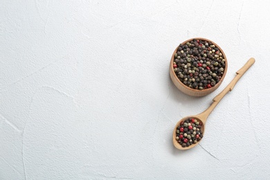 Photo of Bowl and spoon with different peppercorns on light table, top view. Space for text
