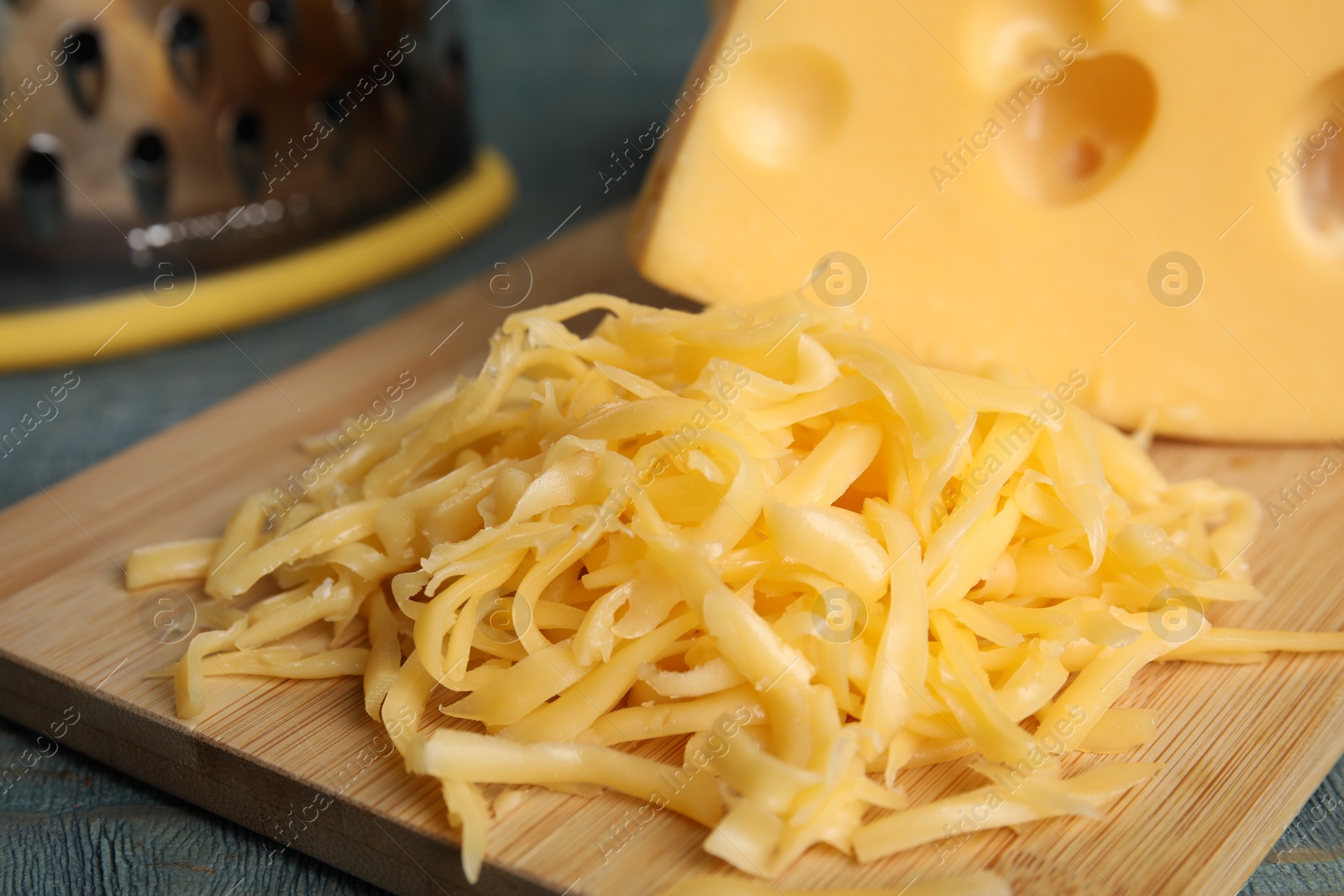 Photo of Tasty grated cheese on wooden table, closeup