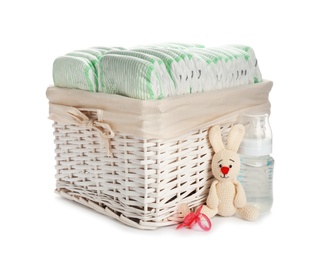 Photo of Wicker basket with disposable diapers and baby accessories on white background