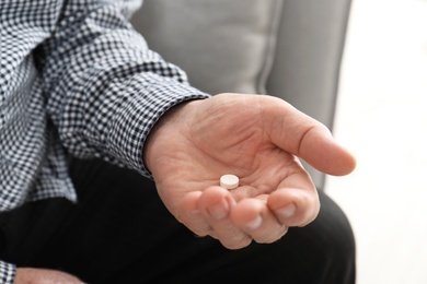 Photo of Senior man holding pill in hand, closeup