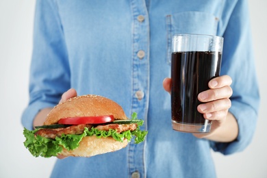 Photo of Woman holding tasty sandwich and glass with cold drink, closeup. Healthy diet