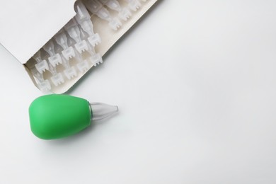 Photo of Package with single dose ampoules of sterile isotonic sea water solution and nasal aspirator on white background, top view. Space for text