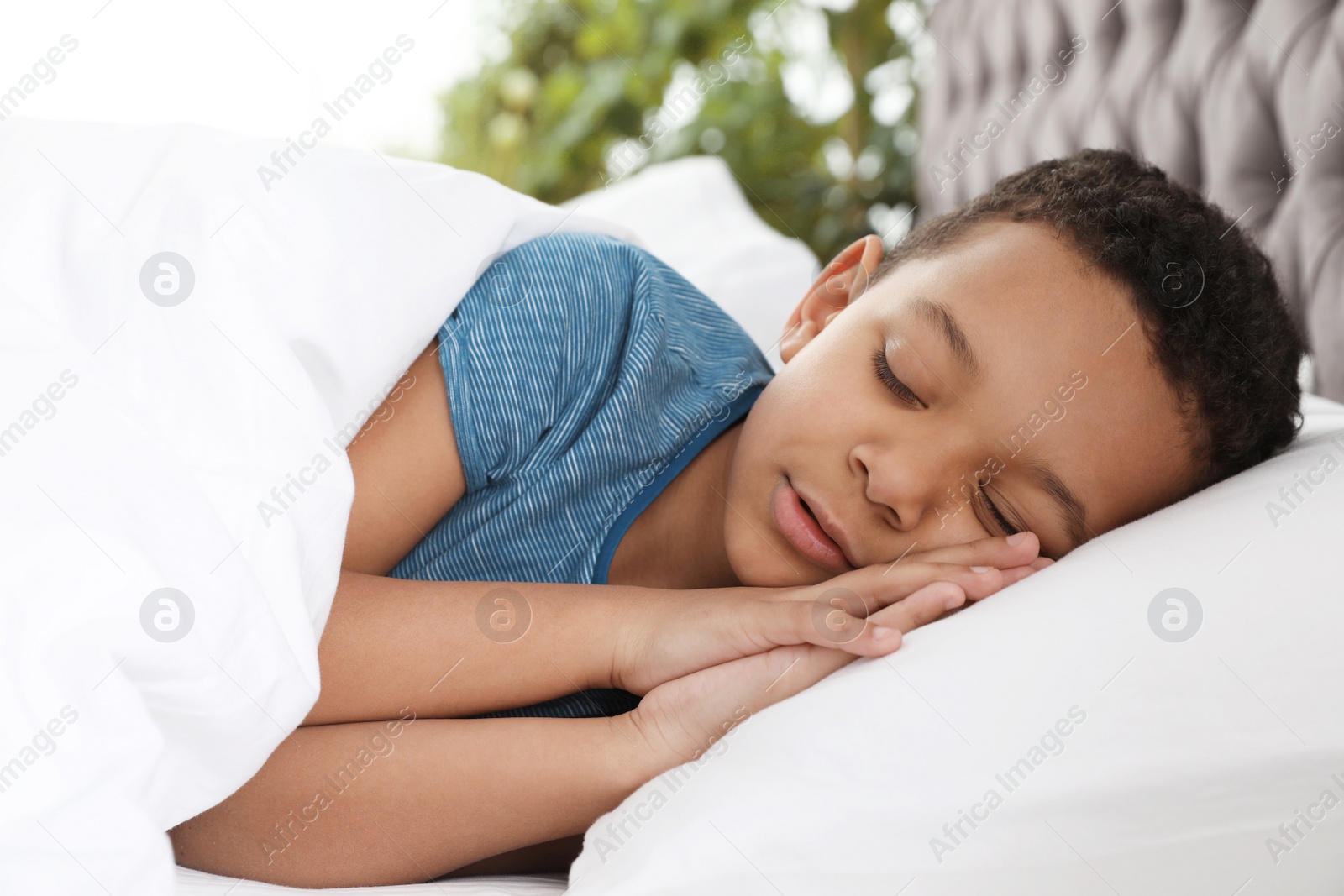 Photo of Cute little African-American boy sleeping in bed