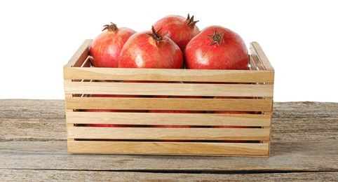 Photo of Fresh pomegranates in crate on wooden table against white background