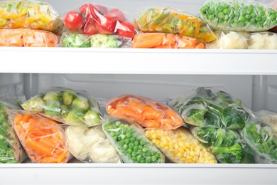 Photo of Plastic bags with deep frozen vegetables in refrigerator